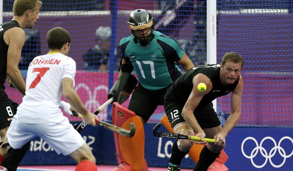 Belgium's John-John Dohmen (7) tries to score a goal as New Zealand's Bradley Shaw (12) defends during their men's hockey preliminary match at the 2012 Summer Olympics.