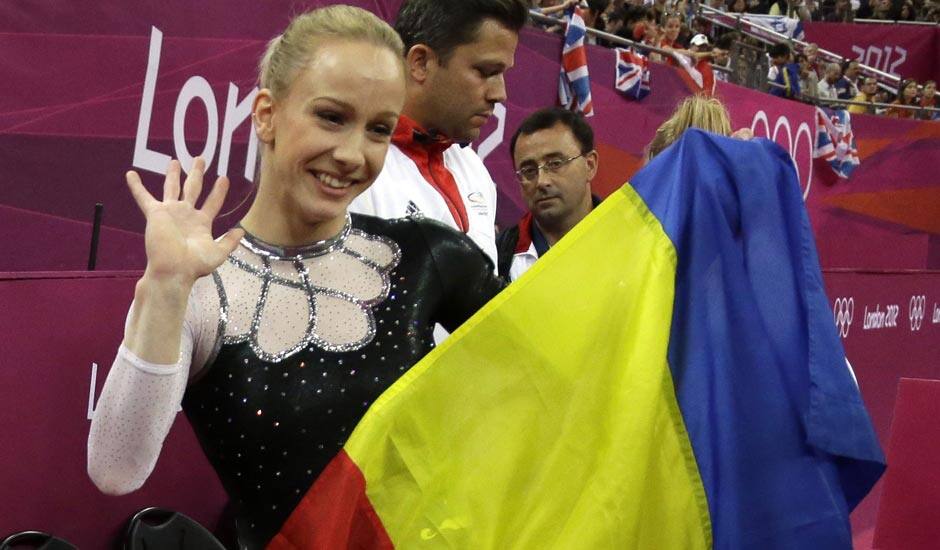 Romania's gymnast Sandra Raluca Izbasa holds her national flag and celebrates after winning the gold medal for the artistic gymnastics women's vault finals at the 2012 Summer Olympics.