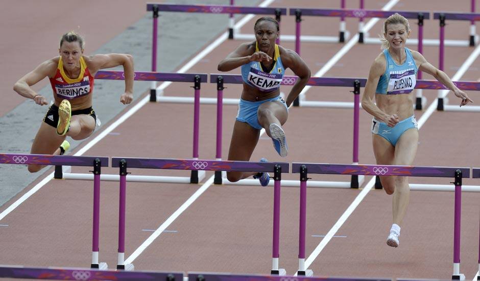 Belgium's Eline Berings, left, Bahamas' Ivanique Kremp, center, and Kazakhstan's Anastassiya Pilipenko, right, compete in a women's 100-meter hurdles heat during the athletics in the Olympic Stadium at the 2012 Summer Olympics.