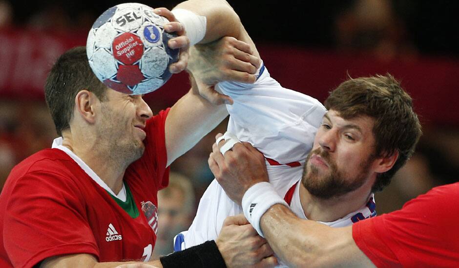 Serbia's Momir Rnic, right, is tackled by Hungary's Ferenc Ilyes, left, during their men's handball preliminary match at the 2012 Summer Olympics in London