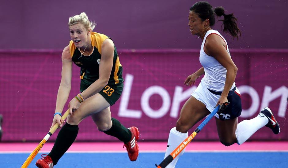 South Africa's Bernadette Coston , left, and Kayla Bashore Smedley vie for the ball in the preliminary round women's hockey match at the 2012 Summer Olympics.