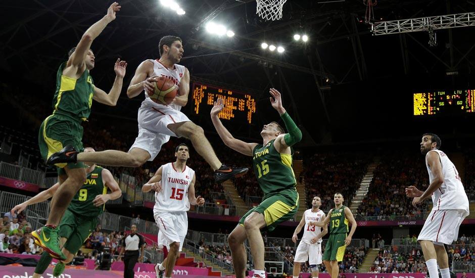 Tunisia's Mourad El Mabrouk, center, looks to pass as he leaps between Lithuania defenders Mantas Kalnietis, left, and Paulius Jankunas (15) during a preliminary men's basketball game at the 2012 Summer Olympics.