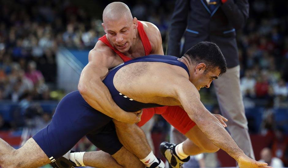 Damian Janikowski of Poland competes against Nazmi Avluca of Turkey (in blue) during the 84-kg Greco-Roman wrestling competition at the 2012 Summer Olympics.