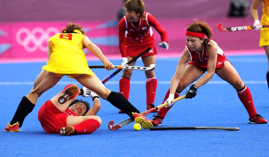 China's Fu Baorong, left, Japan's Keiko Manabe , left on ground, and Nagisa Hayashi vie for the ball in the preliminary round women's hockey match at the 2012 Summer Olympics.