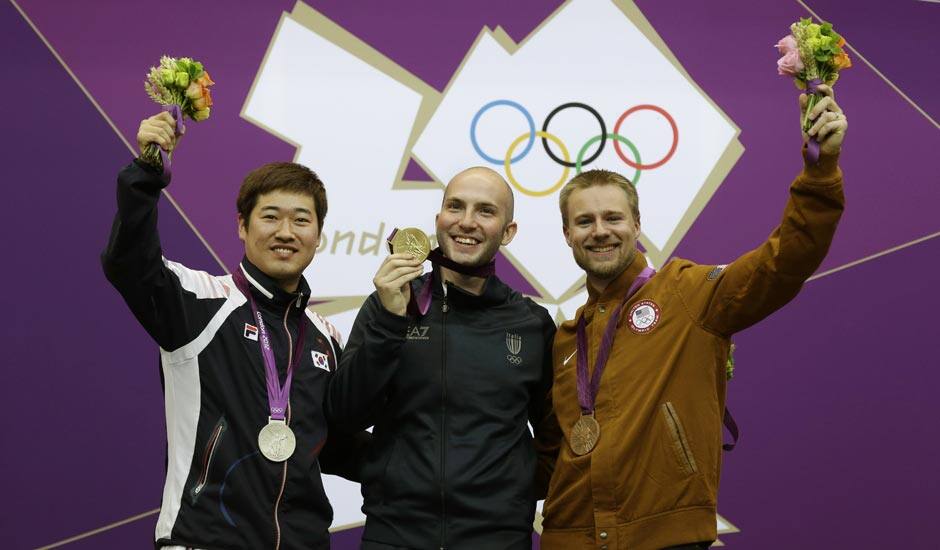 Gold medal winner Italy's Niccolo Campriani, center, poses for a picture with silver medalist Kim Jonghyun of South Korea, left, and bronze medalist Matthew Emmons of the United States of America, during the victory ceremony for the men's 50-meter rifle 3 positions event, at the 2012 Summer Olympics