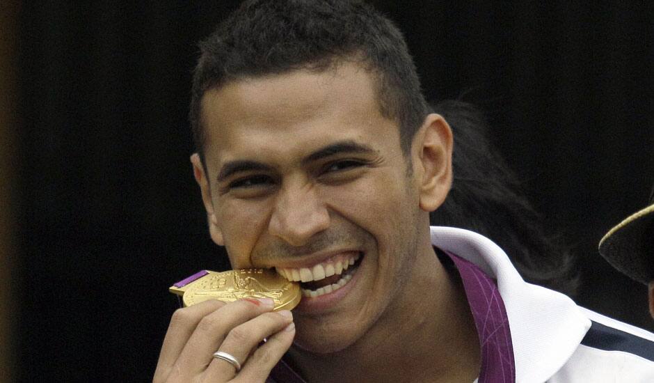 Venezuelan fencer Ruben Limardo bites his gold medal during a welcoming caravan in Caracas, Venezuela, Monday, Aug. 6, 2012. Limardo received a hero's welcome as he returned home Monday after winning a gold medal at the London Olympics.