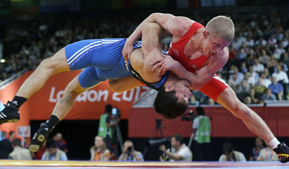 Lithuania's Edgaras Venckaitis is lifted off the mat by Kazakhstan's Darkhan Bayakhmetov (in blue) during their match in 66-kg Greco-Roman wrestling competition at the 2012 Summer Olympics, in London.