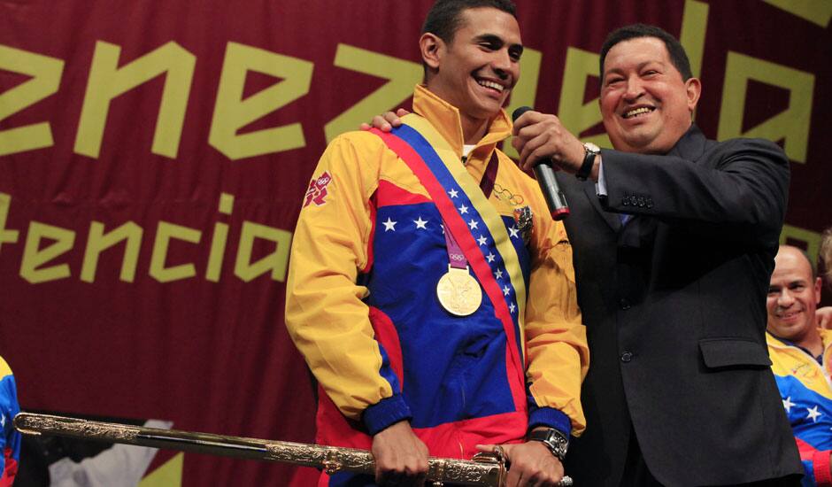 Venezuelan fencer Ruben Limardo, left, holding a replica of a sword once used by South American independence hero Simon Bolivar and Venezuela's President Hugo Chavez, right, smile during a ceremony in Caracas, Venezuela.