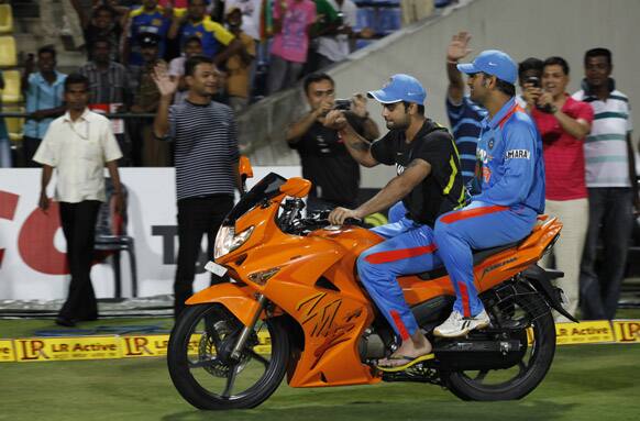 Virat Kohli rides a motorbike that he received for man-of the series with captain Mahendra Singh Dhoni in the back after India beat Sri Lanka in the one-off Twenty20 cricket match in Pallekele.