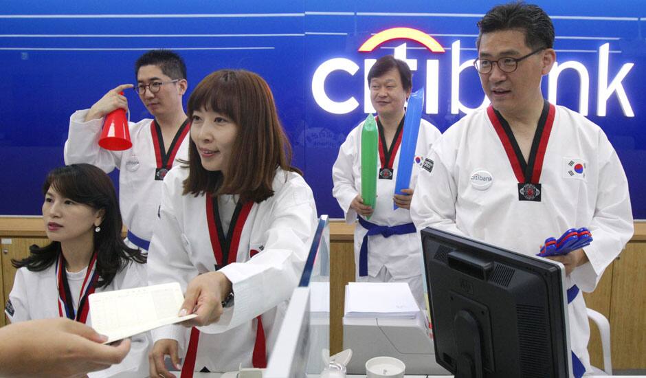 Employees clad in Taekwondo uniform work at a Citibank branch in Seoul. They Wednesday wore the uniforms to show their support for South Koreans competing in Taekwodo at the London Olympics. 