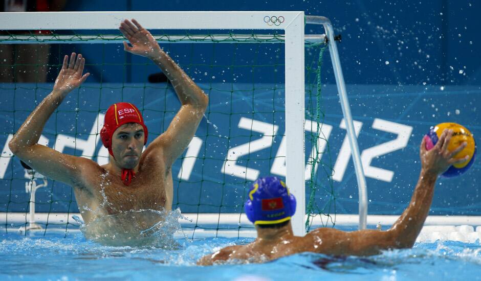 Goalkeeper Inaki Aguilar Vicente, of Spain defends against Drasko Brguljan of Montenegro during a men's quarterfinal water polo match at the 2012 Summer Olympics, in London.