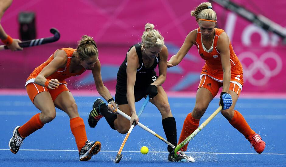 New Zealand's Emily Naylor contests for the ball with Netherlands Kitty van Male, and Eva de Goede in the women's hockey semifinal match at the 2012 Summer Olympics in London.