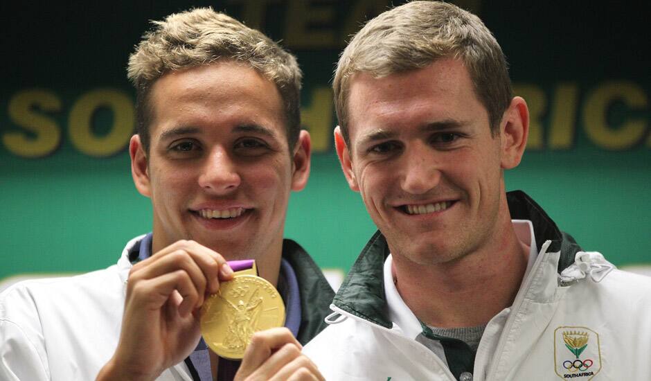 South Africa's swimmers Chad le Clos, with Cameron van der Burgh, poses with his Olympic gold medal during their arrival at OR Tambo International Airport in Johannesburg.