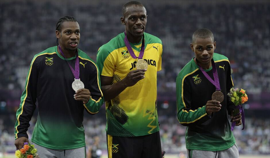 Jamaica's gold medal winner Usain Bolt is flanked by his teammates silver medal winner Yohan Blake, left, and bronze medalist Warren Weir during the ceremony for the men's 200-meter final during the athletics in the Olympic.