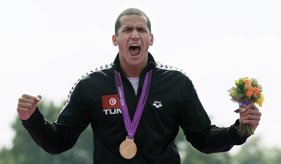 Tunisia's Oussama Mellouli celebrates winning gold during the medal ceremony for the men's 10-kilometer swimming marathon at the 2012 Summer Olympics in London.