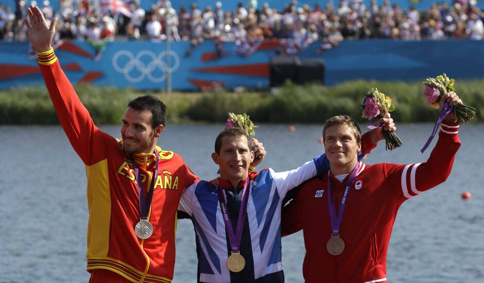 The winners of the men's kayak single 200m pose at the podium in Eton Dorney, near Windsor, England, at the 2012 Summer Olympics. From left to right, Spain's Saul Craviotto Rivero, silver medal, Great Britain's Ed McKeever, gold medal, and Canada's Mark de Jonge, bronze medal.