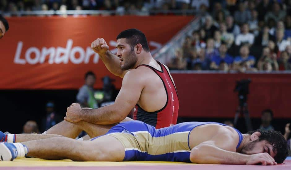 Reza Mohammad Ali Yazdani of Iran, (in red) and Abdusalam Gadisov of Russia, (in blue) finish their 96-kg freestyle wrestling match at the 2012 Summer Olympics.