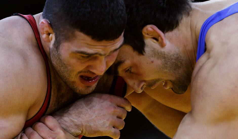 Reza Mohammad Ali Yazdani of Iran, (in red) and Magomed Musaev of Kyrgyzstan, (in blue) compete during their 96-kg freestyle wrestling match at the 2012 Summer Olympics.