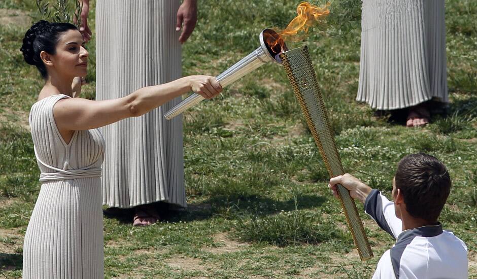 A high priestess, holding a lit torch and an olive branch, performs during the final dress rehearsal for the lighting of the Olympic flame held in Ancient Olympia, Greece