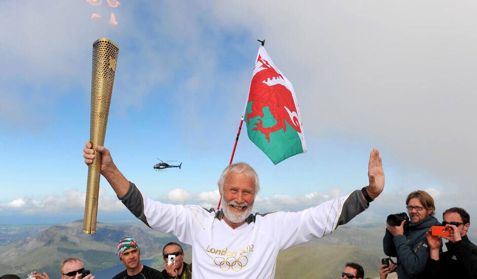 Sir Chris Bonington holding the Olympic Flame on the top of Mount Snowdon in Wales during the Olympic Torch Relay.