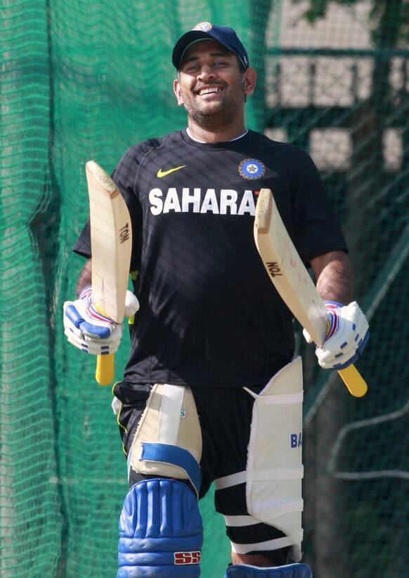 Mahendra Singh Dhoni walks with two bats during a practice session in Hyderabad.