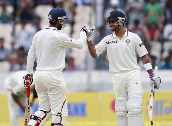 Virat Kohli, congratulates teammate Cheteshwar Pujara for scoring a half century during the first day of the first cricket test match against New Zealand in Hyderabad.