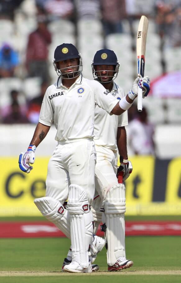 Virat Kohli, celebrates after scoring a half century as teammate Cheteshwar Pujara, looks on during the first day of the first cricket test match against New Zealand in Hyderabad.