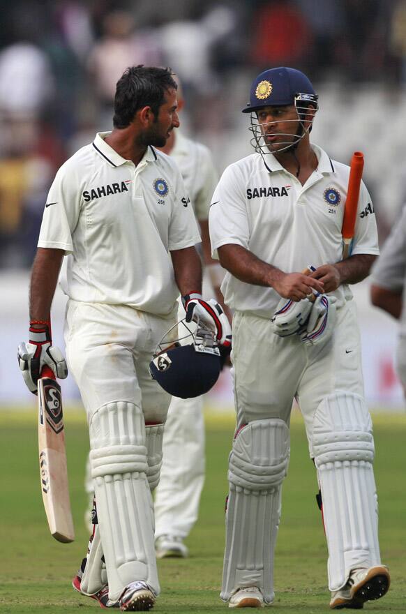 Cheteshwar Pujara, and Mahendra Singh Dhoni leave the ground at the end of the first day of the first cricket test match against New Zealand in Hyderabad.