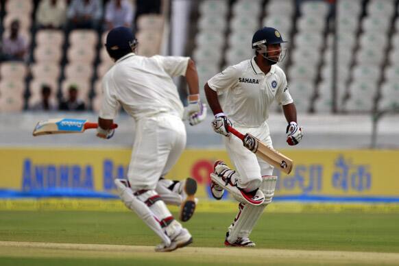 Mahendra Singh Dhoni and Cheteshwar Pujara run between the wickets during the second day of the first cricket test match against New Zealand in Hyderabad.