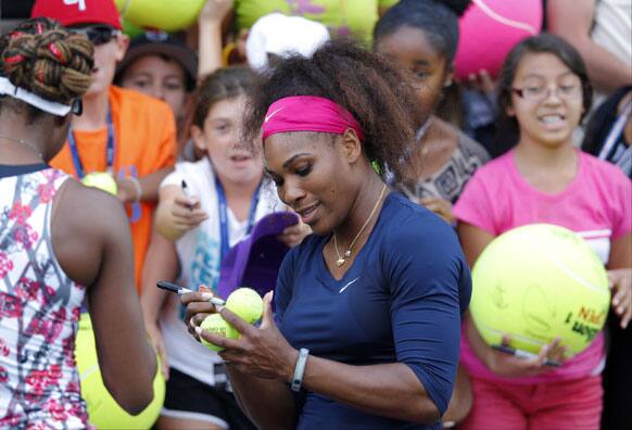 Serena Williams signs autographs for fans after playing in a doubles match with her sister Venus Williams in the second round of play at the 2012 US Open tennis tournament.