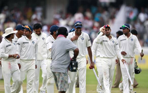 Ravichandran Ashwin carries a stump and a ball as he walks with teammates after India won the first cricket test match against New Zealand in Hyderabad.