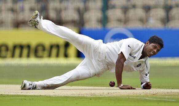 Umesh Yadav falls on the ground in an attempt to stop the ball after a shot played by New Zealand batsman Kane Williamson, during the first day of their second cricket test match in Bangalore.