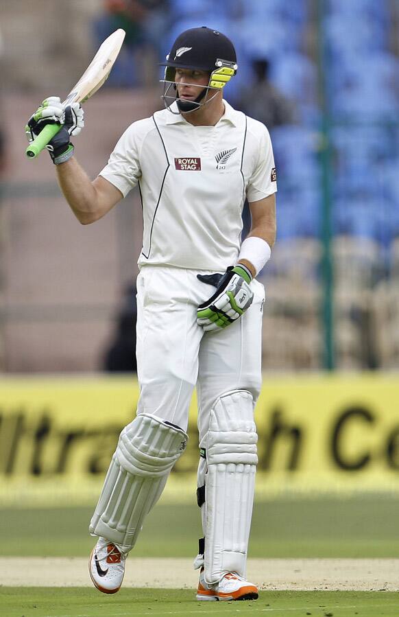 Martin Guptill raises his bat to celebrate scoring a half century during the first day of their second cricket test match against India in Bangalore.