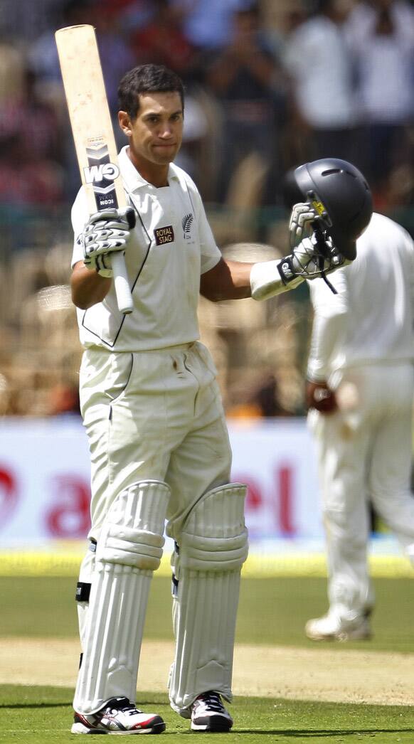 Ross Taylor raises his bat to celebrate scoring a century during the first day of their second cricket test match against India in Bangalore.