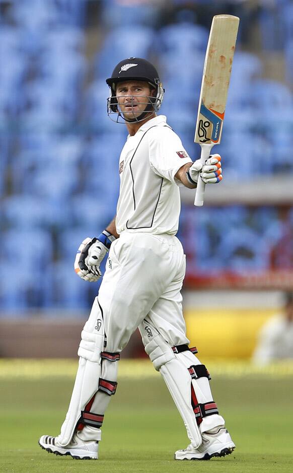 Kruger van Wyk raises his bat to celebrate scoring a half century during the first day of their second cricket test match against India in Bangalore.