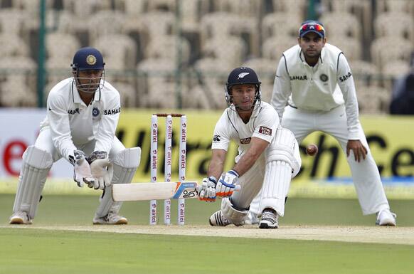 New Zealand batsman Kruger van Wyk, center, prepares to play a shot as India's captain Mahendra Singh Dhoni, left, and Virat Kohli watch during the second day of their second cricket test match in Bangalore.