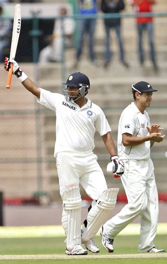 Suresh Raina raises his bat to celebrate scoring a half century as New Zealand captain Ross Taylor applauds during the second day of their second cricket test match in Bangalore.