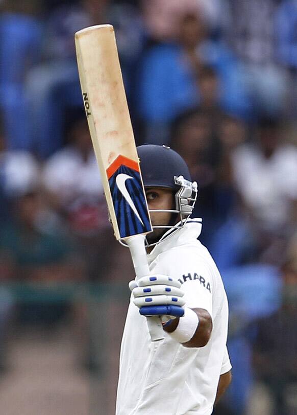 Virat Kohli raises his bat to celebrate scoring a half century during the second day of their second cricket test match against New Zealand in Bangalore.