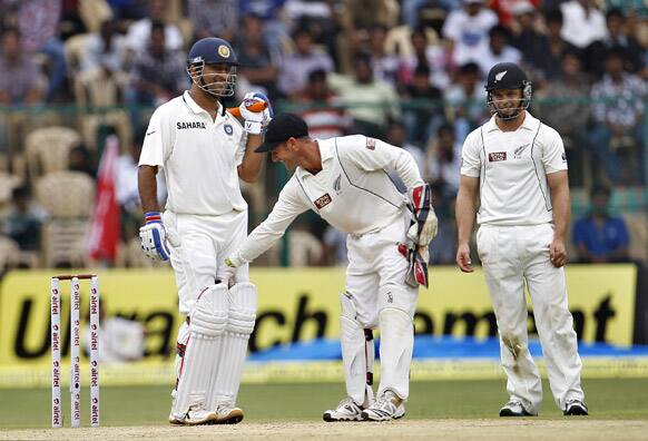 New Zealand wicketkeeper Kruger van Wyk takes the ball held by India's captain Mahendra Singh Dhoni between his legs during the second day of their second cricket test match in Bangalore.