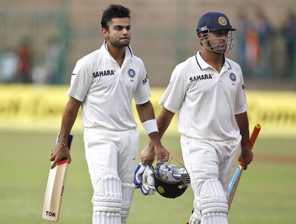 Virat Kohli and captain Mahendra Singh Dhoni leave the ground at the end of the day two of their second cricket test match against New Zealand in Bangalore.