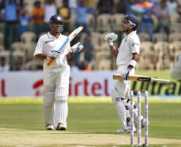 Virat Kohli, right, celebrates scoring a century as captain Mahendra Singh Dhoni, left, applauds during the third day of their second cricket test match against New Zealand in Bangalore.