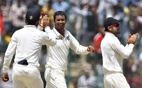 Pragyan Ojha, center, celebrates with teammates the dismissal of New Zealand captain Ross Taylor, not seen, during the third day of their second cricket test match in Bangalore.