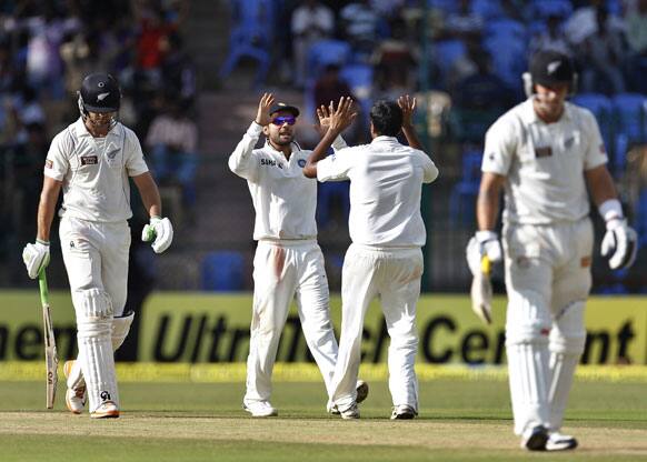 Ravichandran Ashwin, second right, celebrates with teammate Virat Kohli, second left, the dismissal of New Zealand batsman James Franklin, left, during the third day of their second cricket test match in Bangalore.