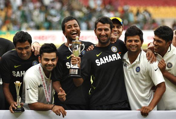 Members of Indian cricket team, from left, Ravichandran Ashwin, Virat Kohli, Pragyan Ojha, Cheteshwar Pujara, Suresh Raina and Umesh Yadav pose with the winners trophy after their win over New Zealand on the fourth day of their second cricket test match in Bangalore.