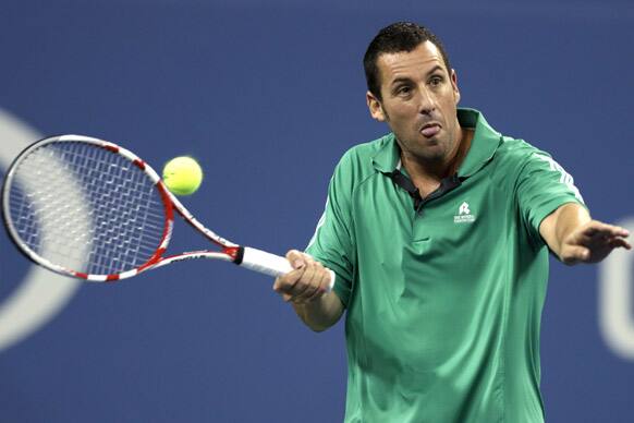 Comedian Adam Sandler hits a return during an exhibition match at the U.S. Open tennis tournament.