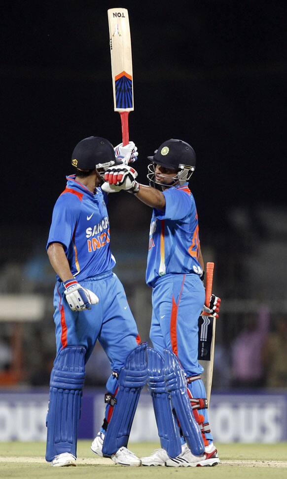 Indian cricketers Virat Kohli, left, raises his bat after scoring fifty runs as teammate Suresh Raina congratulates him during the second and final Twenty20 international cricket match between India and New Zealand in Chennai.