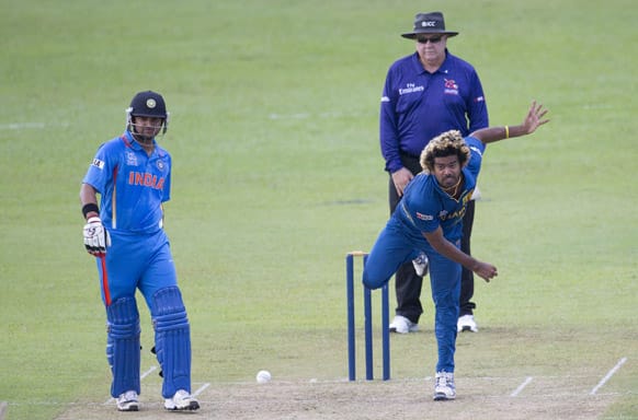 Sri Lanka's Lasith Malinga , right foreground, bowls as non-striker India's Suresh Raina, left, watches during a practice match between Sri Lanka and India ahead of the ICC T20 cricket World Cup in Colombo.