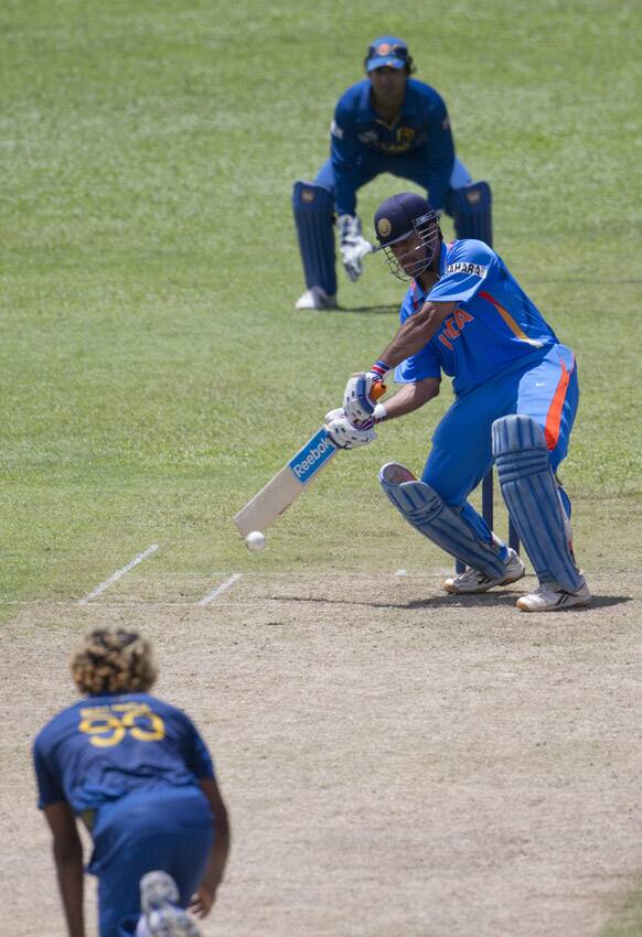 Mahendra Singh Dhoni, center, bats as Sri Lanka's bowler Lasith Malinga, left foreground, delivers a ball during a practice match between Sri Lanka and India ahead of the ICC T20 cricket World Cup in Colombo.