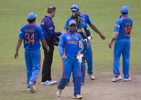 Mahendra Singh Dhoni center facing watches as teammates congratulate each other after India beat Sri Lanka during a practice match ahead of the ICC T20 cricket World Cup in Colombo.