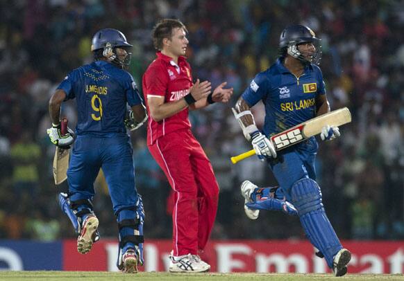 Sri Lanka's Jeewan Mendis, left and Kumar Sangakkara, right run between the wickets as Zimbabwe's bowler Kyle Jarvis,center watches during the ICC Twenty20 Cricket World Cup match between Sri Lanka and Zimbabwe in Hambantota.